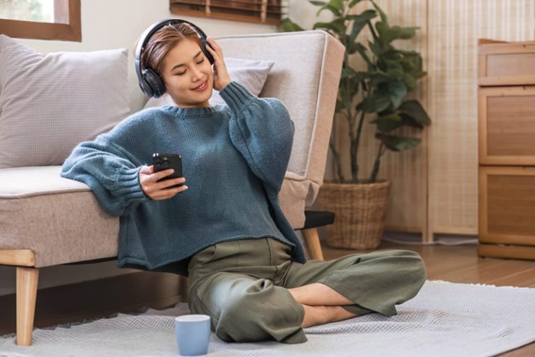 A woman is sitting on the floor engrossed in playing a game